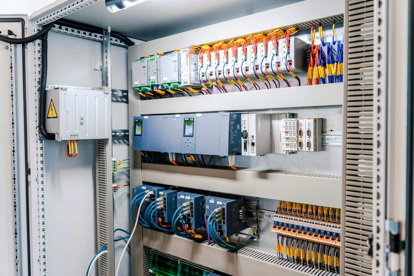 Elektrischer Schaltschrank mit geordneten Modulen und bunten Kabeln.